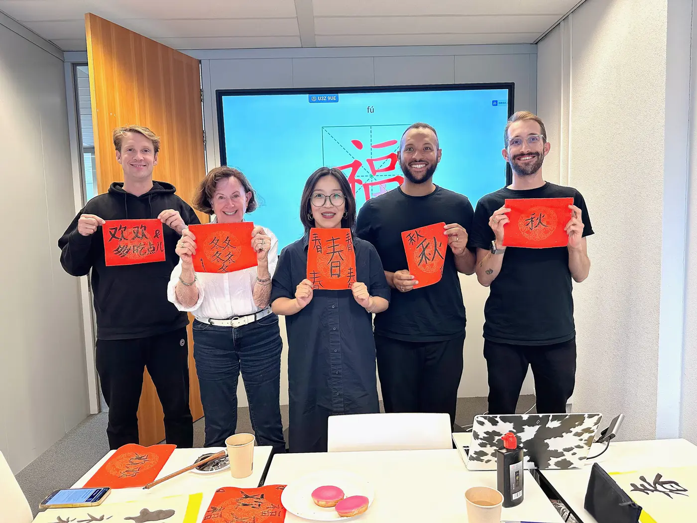 Chinese calligraphy workshop for companies: a team holding the characters they wrote on red paper